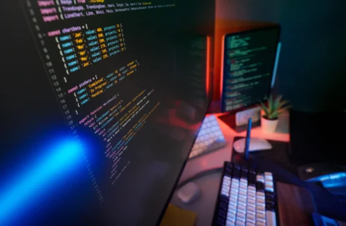 A monitor with a code editor shown on a desk with a keyboard 